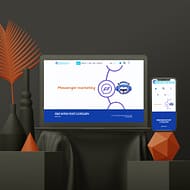 A computer monitor displaying a website with the header "Messenger Marketing" and a smartphone showing the same website. The devices are on a dark surface, surrounded by modern black and orange geometric decorations and vases with red leaves, highlighting sleek web design elements.